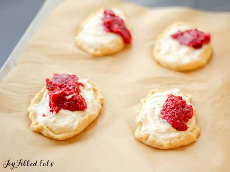 Parchment lined baking sheet with raspberry cream cheese danishes