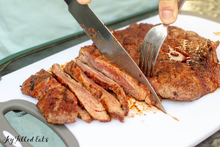 steak with fajita seasoning being sliced on a cutting board