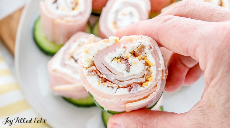 a hand holding on of the bacon turkey pinwheels