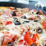 skillet meatzza with cheese and olives close up