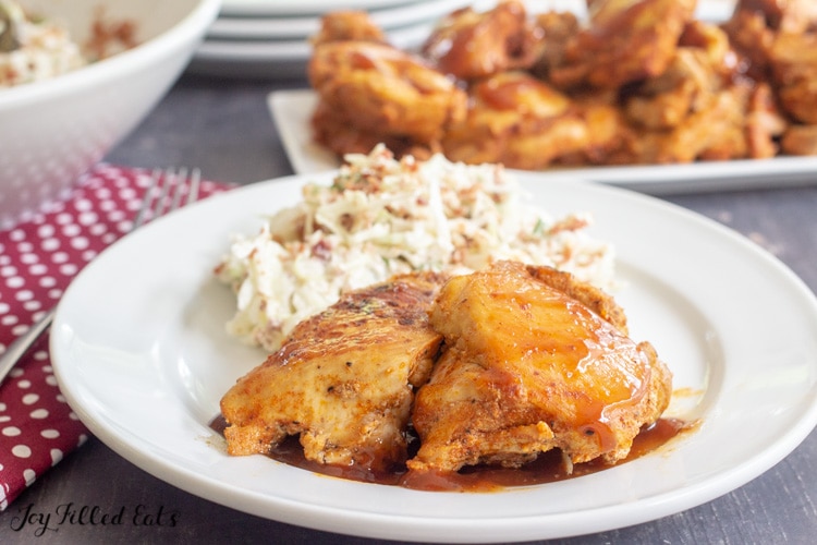 a round white plate with 2 pieces of the instant pot barbecue chicken thighs and keto coleslaw 