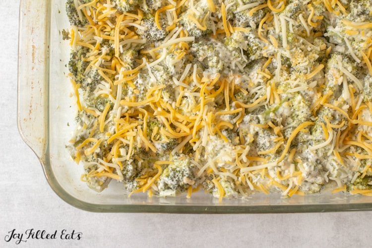 cheese on top of a broccoli casserole in a baking dish