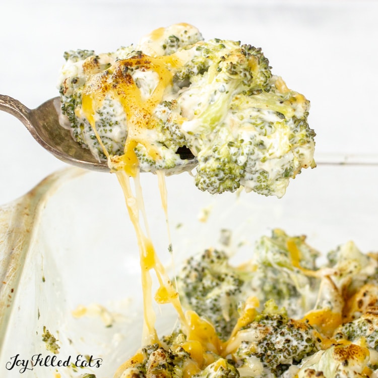 a spoon lifting up broccoli with melted cheese