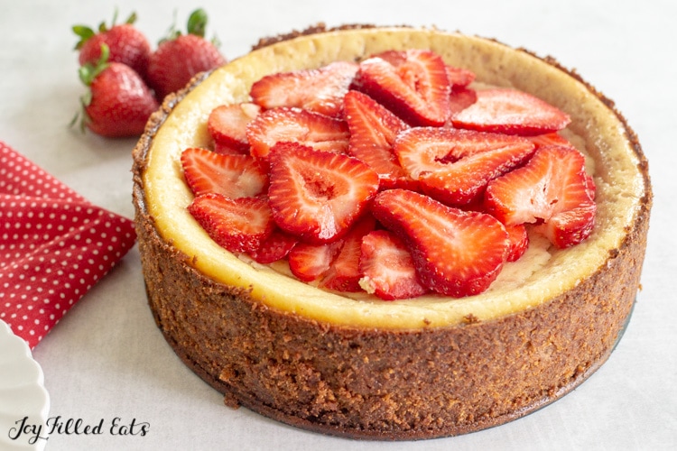 an entire cheesecake with an almond crust topped with strawberries