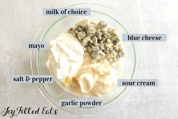 glass bowl of ingredients including mayo, sour cream, and garlic powder