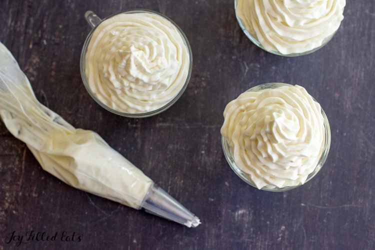 a piping bag next to three bowls of whipped cheesecake