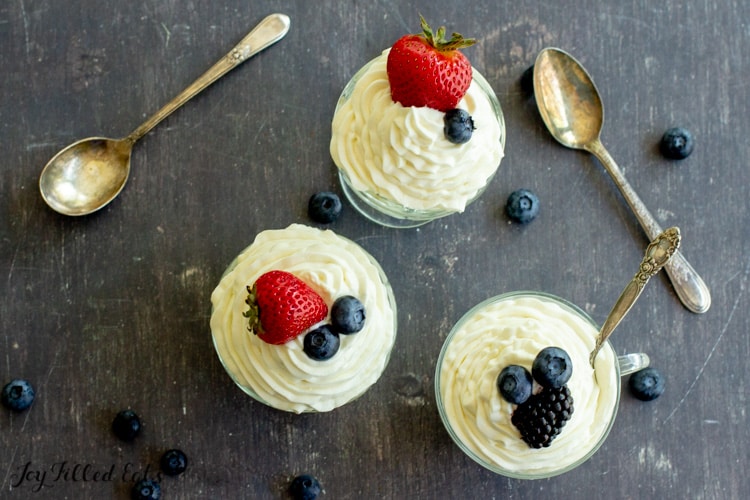 three bowls of keto cheesecake fluff topped with berries