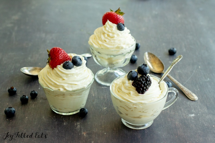 three bowls of keto cheesecake fluff topped with berries with spoons