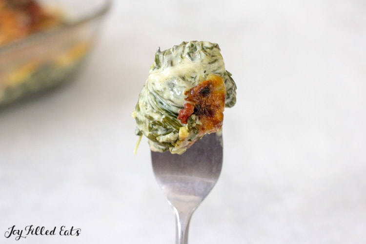a bite of keto creamed spinach held up on a fork