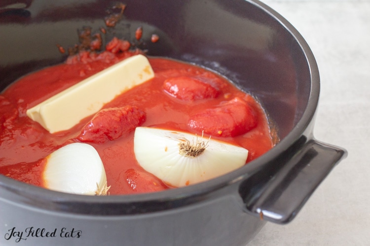 canned tomatos in a pot with onion and butter
