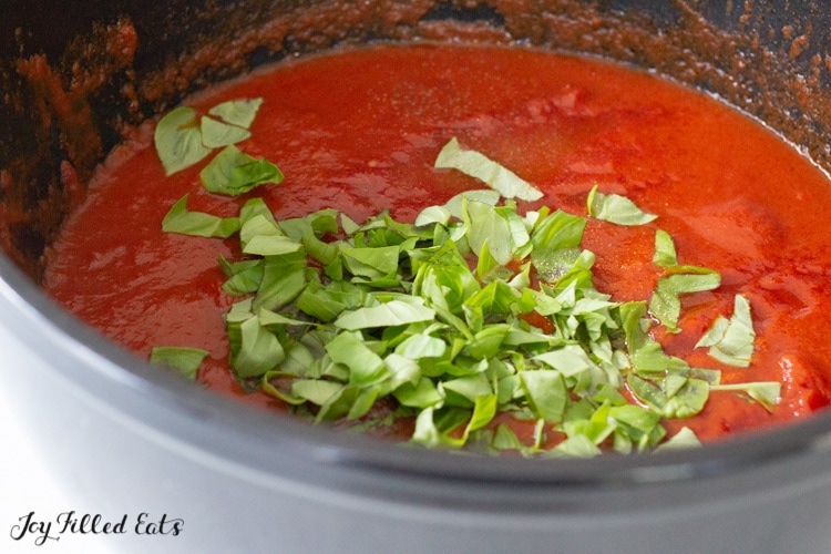 chopped fresh basil on top of tomato sauce in a large pot