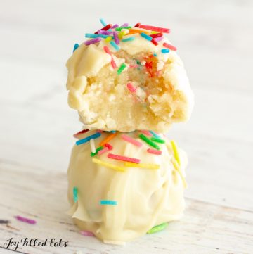 close up of two cake batter truffles stacked on top of each other with a bite missing