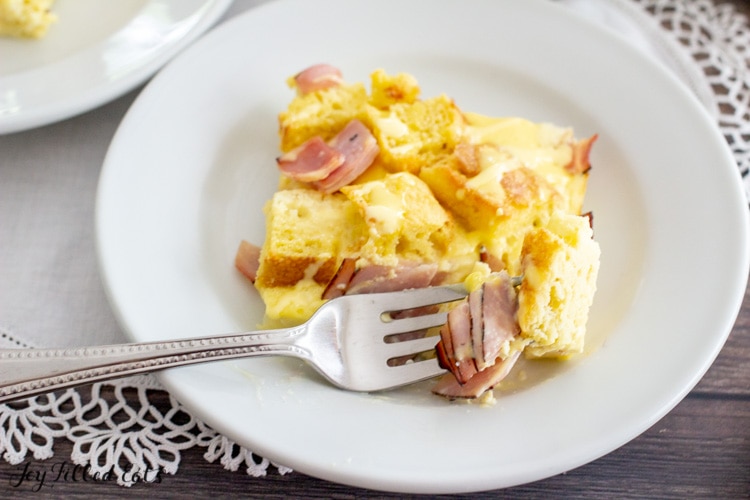 a bite of the keto eggs benedict casserole on a fork on a white plate