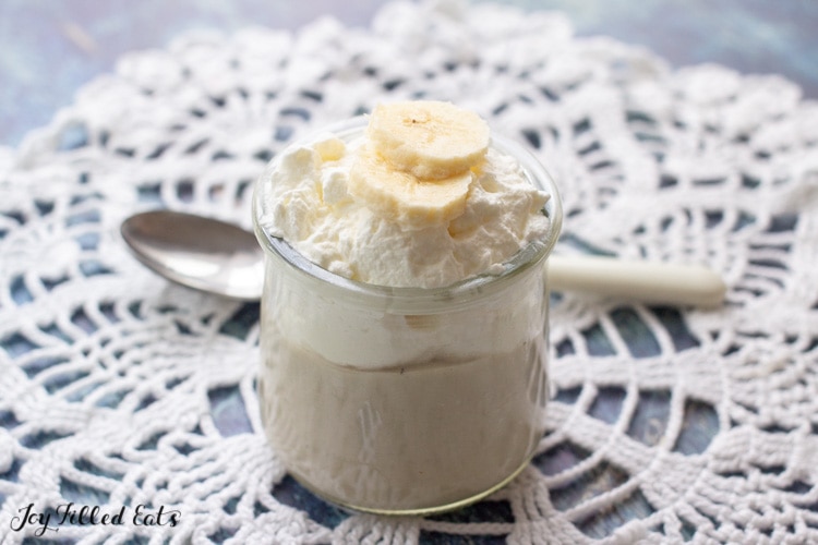 a single serving of pudding layered with whipped cream with a spoon