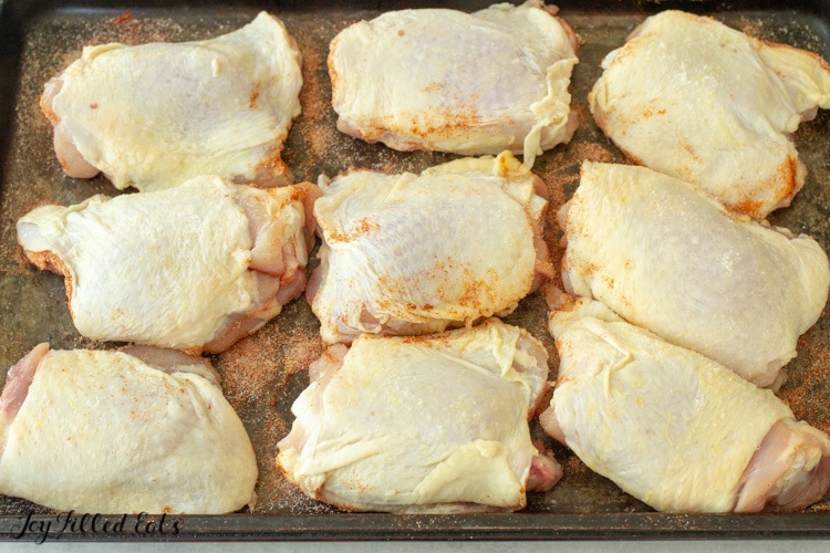 chicken thighs on a cooking sheet skin side up sprinkled with salt