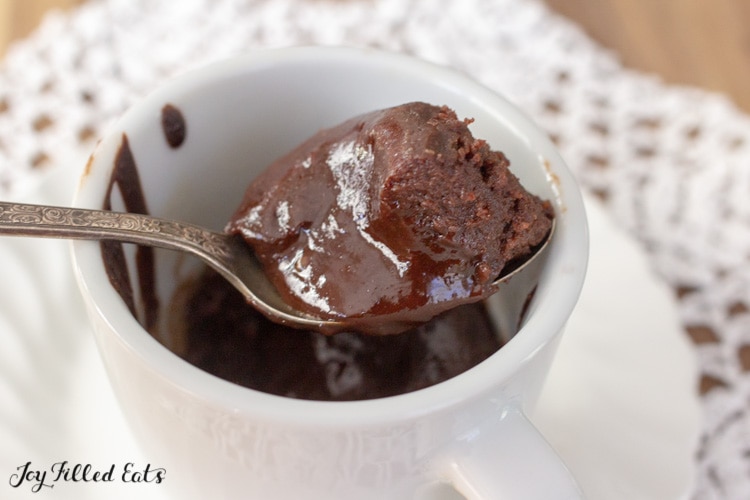 a spoon lifting some keto chocolate lava cake out of a mug