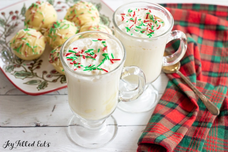 two mugs of peppermint white hot chocolate with hot chocolate bombs in the back