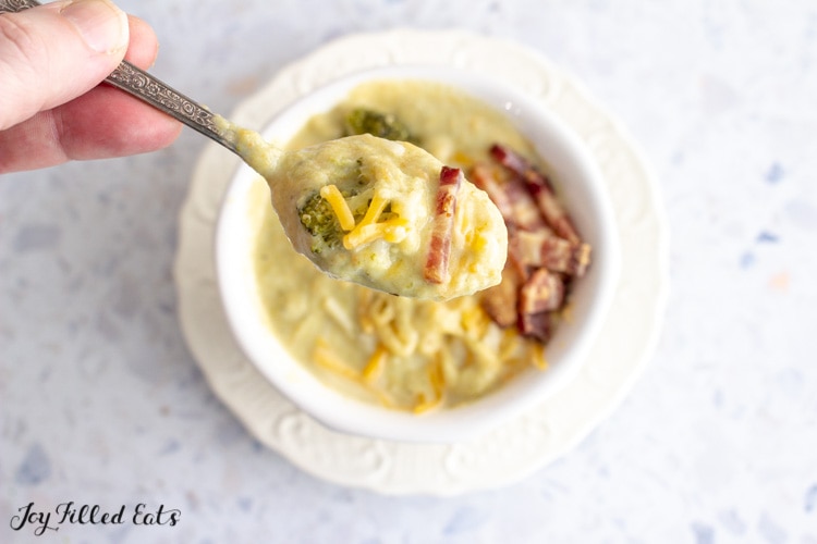hand holding a spoon lifting keto broccoli cheese soup with bacon