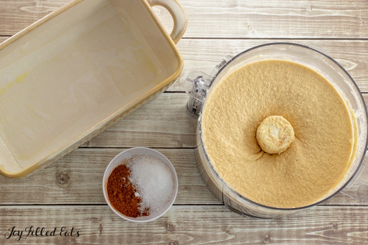 food processor with batter next to a parchment lined loaf pan