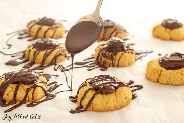 a spoon drizzling chocolate on top of chocolate hazelnut cookies