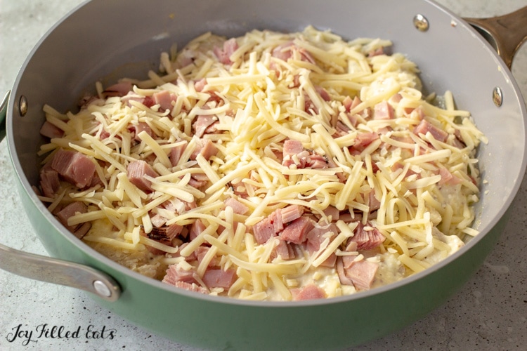 skillet with chicken, sauce, ham, and cheese