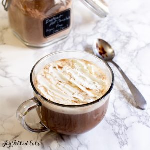sugar free hot chocolate mix in a jar next to a mug of hot cocoa
