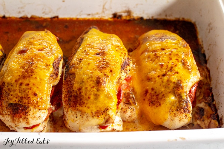 four fajita stuffed chicken breasts in a baking dish topped with cheese