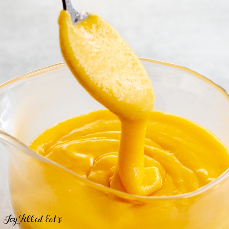 a spoon lifting up some of the keto cheese sauce