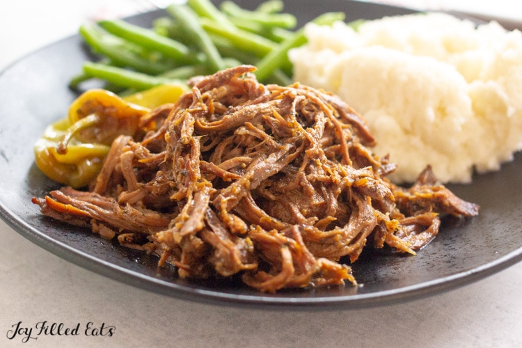close up of keto mississippi pot roast on a plate with mashed cauliflower and green beans