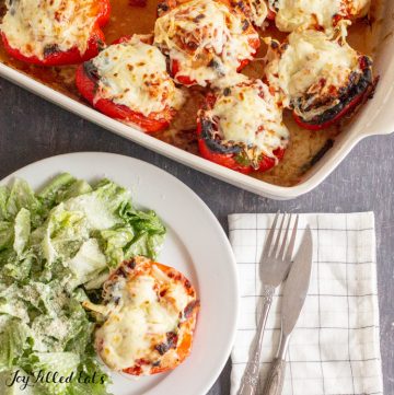 overhead shot of the chicken parm stuffed peppers on a plate with a salad and in the casserole dish