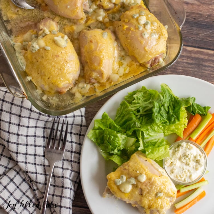 baking dish of buffalo chicken thighs and one on a plate with salad