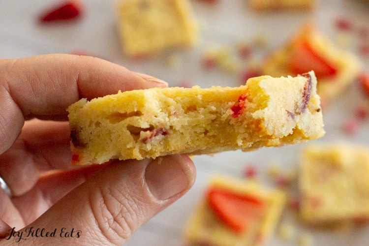 a hand holding one of the keto strawberry blondies with a bite missing