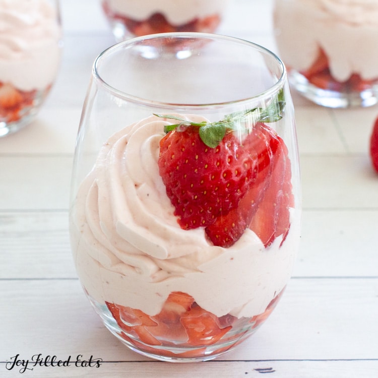 keto strawberry mousse in a wine glass with a sliced fanned out strawberry