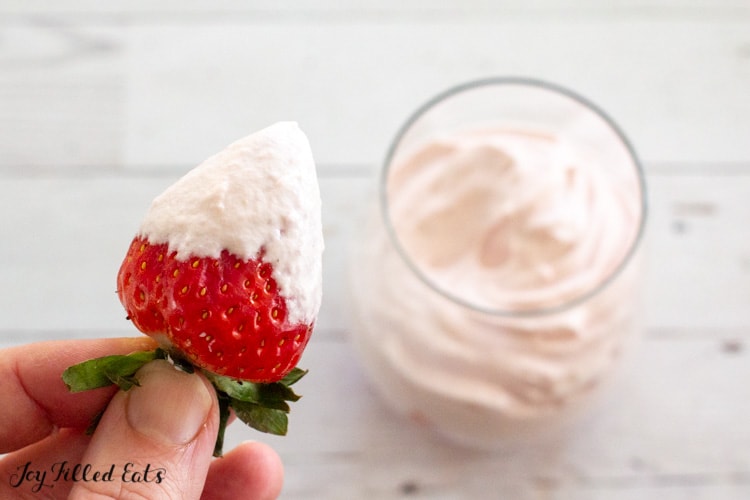 hand holding a strawberry that was dipped in the low carb mousse