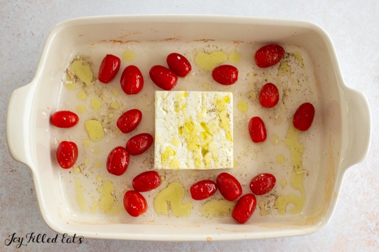 casserole dish with a block of feta and tomatoes