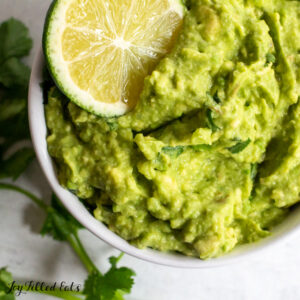 close up of keto guacamole with a lime