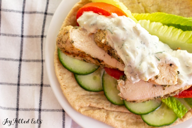 close up of a pita with vegetables, grilled chicken, and keto tzatziki sauce