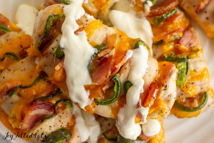 jalapeno popper hasselback chicken stacked on a plate and drizzled with cream sauce