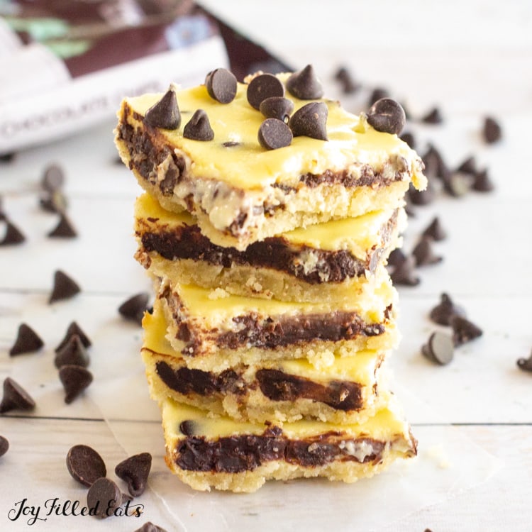 stack of keto chocolate chip cheesecake bars with a bag of chocolate chips behind