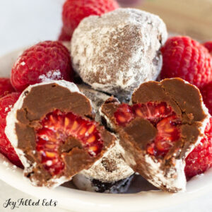 close up of one of the dark chocolate raspberry truffles cut in half showing the raspberry inside