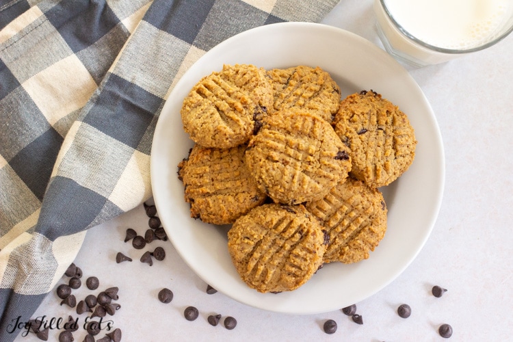 overhead shot of keto peanut butter chocolate chip cookies on a plate with a glass of milk