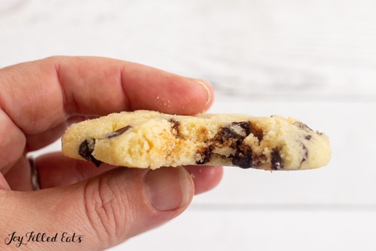 hand holding a single serve chocolate chip cookie missing a bite