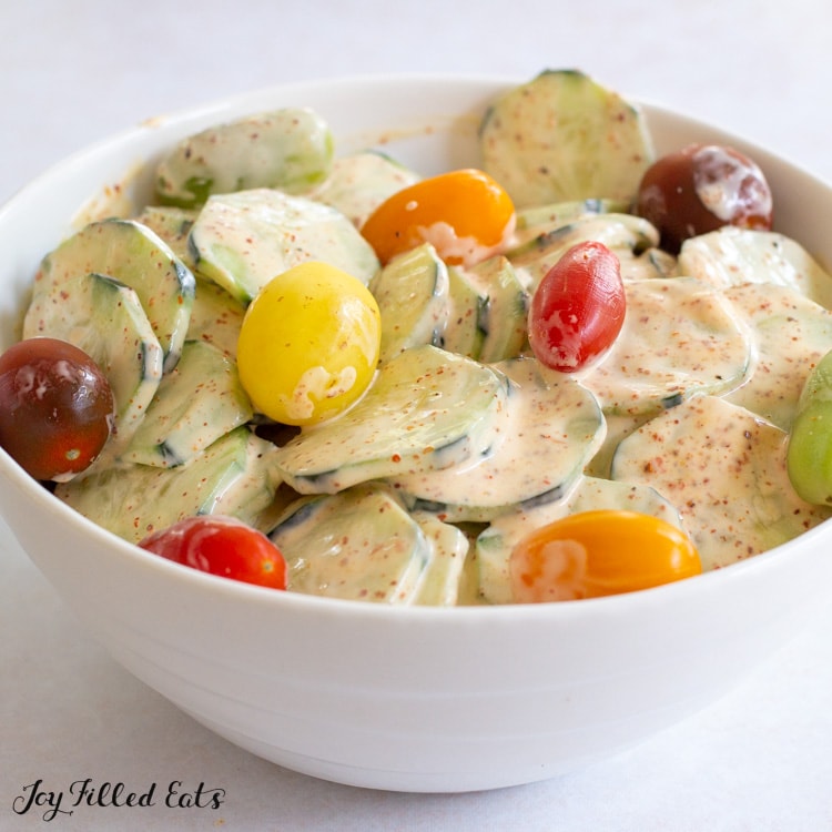 bowl of tajin cucumber salad topped with tomatoes