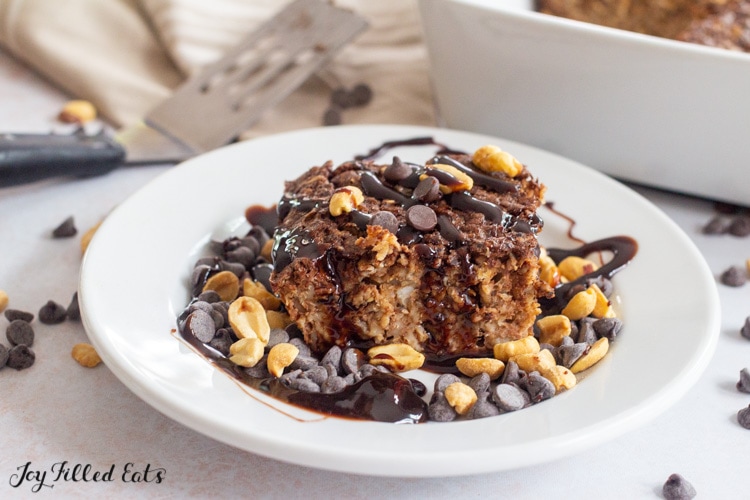 baked protein oatmeal on a plate topped with chocolate sauce and peanuts