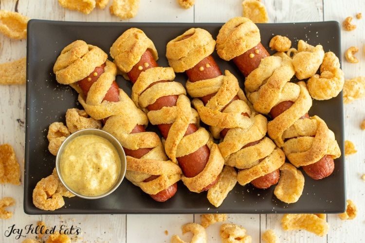 rectangle plate of keto mummy dogs surrounded by pork rinds