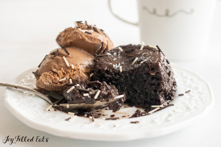 flourless mug cake on a plate with a spoon and chocolate ice cream