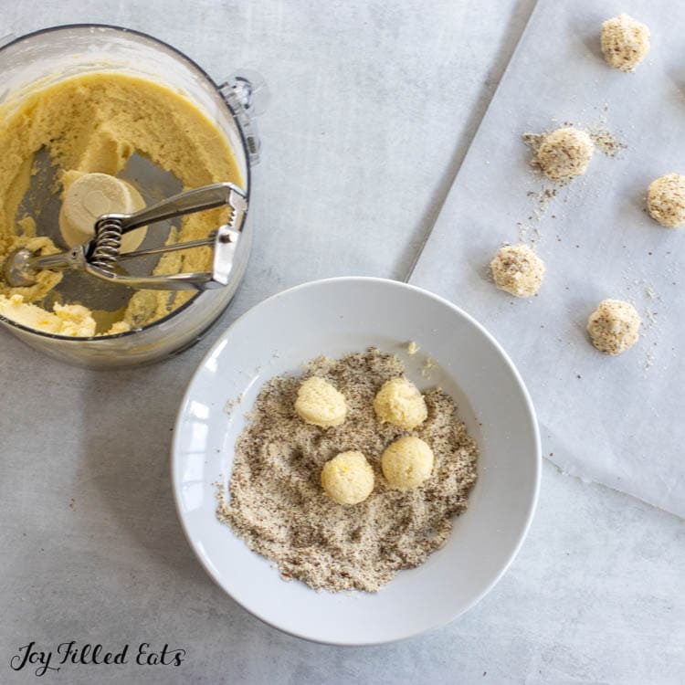 dough in food processor and dough balls in bowl of almond meal