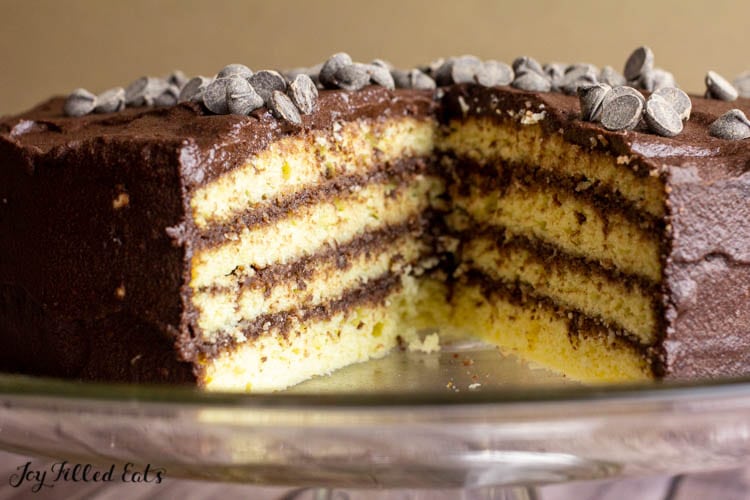 yellow birthday cake with chocolate icing with slice missing displaying cake and icing layers