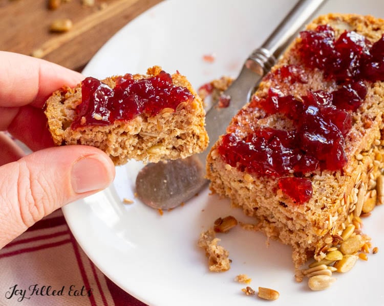 hand holding a bite sized piece of the sprouted quinoa bread with jam on it