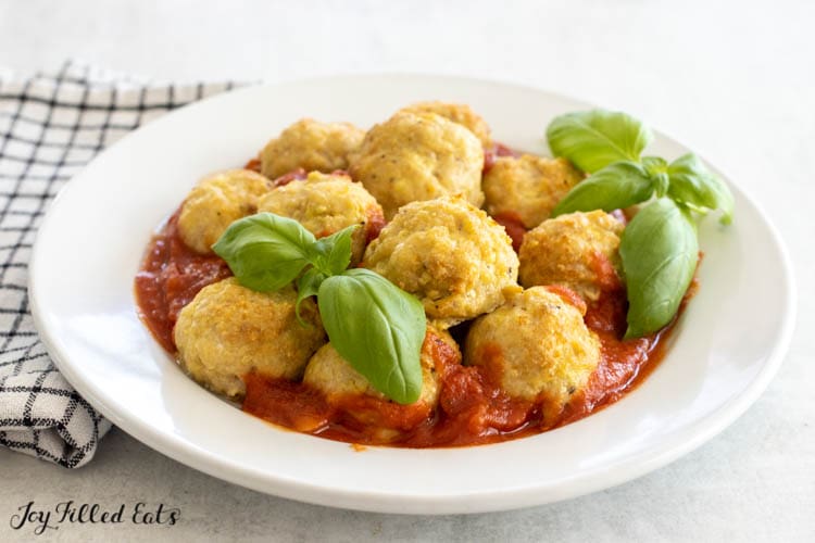 air fryer chicken meatballs on a plate with marinara sauce and basil